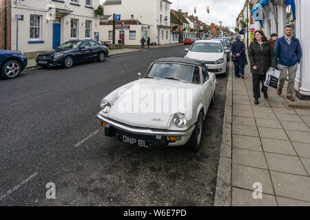 Une femme jette un regard admiratif de l'acheteur à un Spitfire blanc classique voiture de sport, High Street, Stony Stratford, UK Banque D'Images