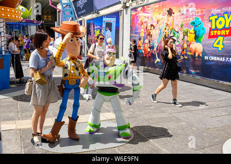 Une femme possède à côté des répliques de shérif Woody et Buzz Lightyear pendant le Carnaval.Toy Story 4 est célébré avec un carnaval sur le thème de jeux différents et les défis à relever sur le port de Hong Kong City. Banque D'Images