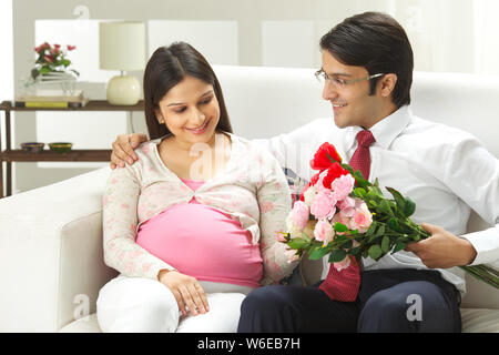 Homme d'affaires donnant un bouquet de fleurs à sa femme enceinte Banque D'Images