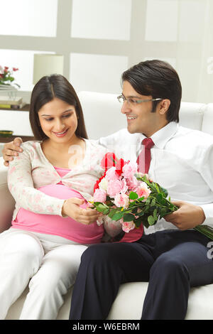 Homme d'affaires donnant un bouquet de fleurs à sa femme enceinte Banque D'Images