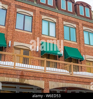 Square de l'extérieur d'un bâtiment en briques rouges avec des auvents verts sur le balcon fenêtres Banque D'Images