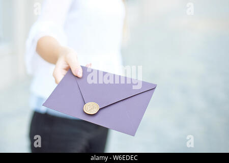 Jeune fille est titulaire d'invitation par courrier électronique cartes dans sa main. Enveloppes avec cachet de cire dans les mains close-up Banque D'Images