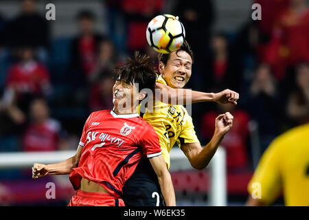 Joueur de football sud-coréen Kim Young-gwon, droite, de Guangzhou Evergrande en Chine Taobao FC chefs la balle contre un joueur de Jeju en Corée du Sud Un Banque D'Images