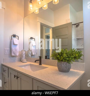 Miroir carré et lavabo à l'intérieur d'une salle de bains avec murs blancs et parquet en bois brun Banque D'Images