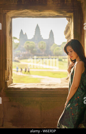 Portrait de Candide asiatique brune femelle solo traveler avec à Siem Reap, Cambodge. Il y a un célèbre temple d'Angkor Wat dans l'arrière-plan. Banque D'Images