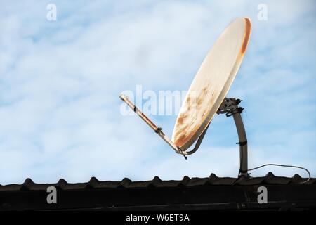 Brisée et vieille antenne satellite sur le toit et fond de ciel bleu. Banque D'Images