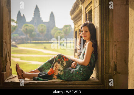 Portrait de Candide asiatique brune femelle solo traveler avec à Siem Reap, Cambodge. Il y a un célèbre temple d'Angkor Wat dans l'arrière-plan. Banque D'Images