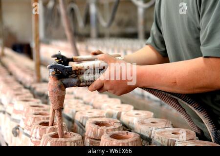 --FILE--Un travailleur chinois produit des bouteilles en porcelaine Xia occidentaux utilisés pour contenir l'esprit chinois d'une usine à Wuwei ville du nord-ouest de la Chine, au Gansu Banque D'Images