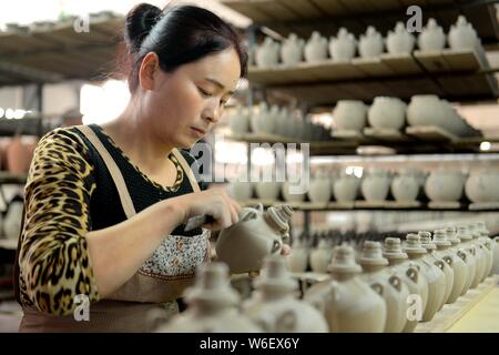 --FILE--Un travailleur chinois produit des bouteilles en porcelaine Xia occidentaux utilisés pour contenir l'esprit chinois d'une usine à Wuwei ville du nord-ouest de la Chine, au Gansu Banque D'Images
