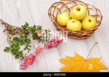 Des pommes mûres dans l'osier busket, feuille sèche et de fleurs sur un bureau en bois. Une saine alimentation biologique. Thème de l'automne. Vue d'en haut. Banque D'Images