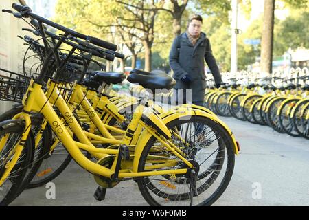 --FILE--un résident local marche dernières bicyclettes des vélos en libre-service chinois ofo alignés sur une route à Shanghai, Chine, 13 janvier 2018. Bik chinois Banque D'Images