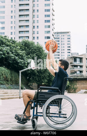 Homme handicapé en fauteuil roulant de jeter au panier balle seulement, concept d'adaptive sports et l'activité physique, la réadaptation des personnes ayant une di Banque D'Images