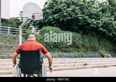 Homme handicapé en fauteuil roulant à la cour de basket-ball, le seul concept de adaptive sports et l'activité physique, la réadaptation des personnes ayant une di Banque D'Images
