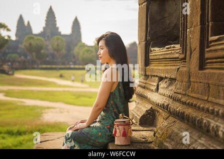 Portrait de Candide asiatique brune femelle solo traveler avec à Siem Reap, Cambodge. Il y a un célèbre temple d'Angkor Wat dans l'arrière-plan. Banque D'Images