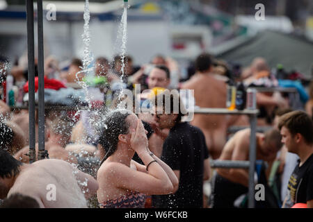 Kostrzyn Nad Odra, Pologne. 06Th Aug 2019. Un visiteur frotte son visage sous une douche sur le terrain de la Pol'et'Rock Festival. Le festival gratuit pour les visiteurs aura lieu du 01.08.2019 au 03.08.2019 pour la 25e fois à Kostrzyn nad Odra. Credit : Gregor Fischer/dpa/Alamy Live News Banque D'Images