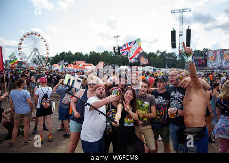 Kostrzyn Nad Odra, Pologne. 06Th Aug 2019. Un groupe de visiteurs selfies fera une en face de l'un des stades et la grande roue sur le terrain de la Pol'et'Rock Festival. Le festival gratuit pour les visiteurs aura lieu du 01.08.2019 pour la 25e fois, jusqu'à 03.08.2019 à Kostrzyn nad Odra. Credit : Gregor Fischer/dpa/Alamy Live News Banque D'Images