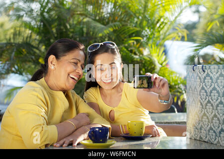 Fille avec sa mère prenant la photo d'eux-mêmes avec un appareil photo numérique Banque D'Images