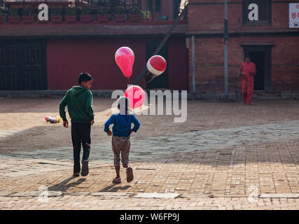 Garçon et fille avec des ballons roses marche à travers un carré à Katmandou, au Népal. Banque D'Images