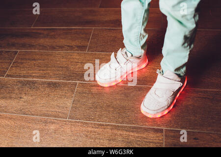 La mode des chaussures avec éclairage LED sur les jambes d'une fille . La même couleur de l'éclairage LED sneakers.cadre vertical. Banque D'Images