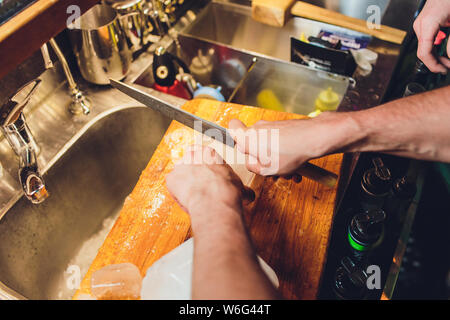 Barman est la coupe d'un grand bloc de glace pour préparer des cocktails de whisky. Selective focus sur le bloc de glace. L'hospitalité et bon whisky concept. Banque D'Images