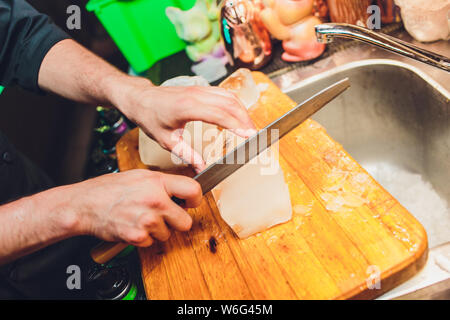 Barman est la coupe d'un grand bloc de glace pour préparer des cocktails de whisky. Selective focus sur le bloc de glace. L'hospitalité et bon whisky concept. Banque D'Images