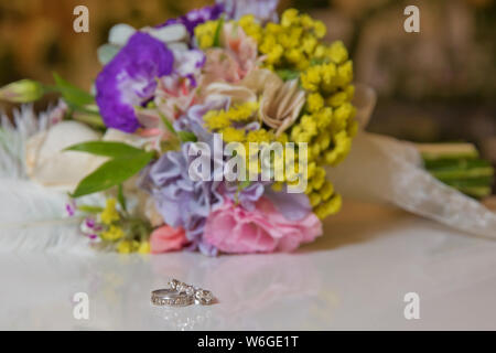 Les anneaux de mariage et magnifique bouquet comme accessoires pour mariée . Belle photo aux couleurs avec bagues de se coucher sur une surface en bois contre le backgrou Banque D'Images