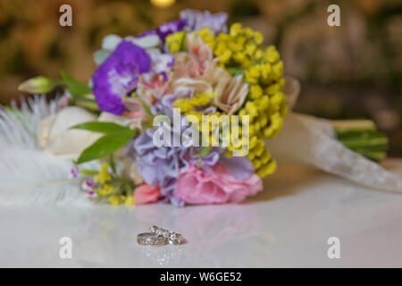Les anneaux de mariage et magnifique bouquet comme accessoires pour mariée . Belle photo aux couleurs avec bagues de se coucher sur une surface en bois contre le backgrou Banque D'Images