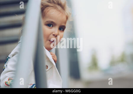 Cheerful family en ville. Cute little girl posant pour l'appareil photo dans la rue. Banque D'Images