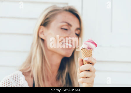 Blonde girl eating ice cream de fusion dans un cône Banque D'Images