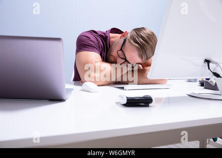 Épuisé Businessman Sleeping On en face de Computer at Office Banque D'Images