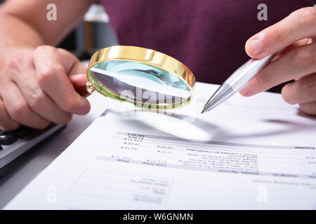 Close-up of a Hand Holding du comptable Contrôle de loupe le projet de loi sur le lieu de travail Banque D'Images