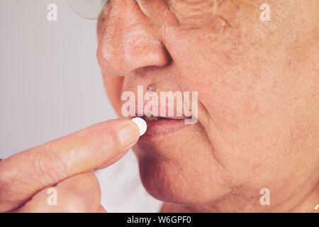 Senior mature femme d'âge moyen holding pill painkiller prendre pour soulager la douleur, la médecine les vitamines, les médicaments antibiotiques, médicaments aux vieux par Banque D'Images