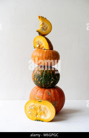 Une haute pyramide d'une variété de pièces et de citrouilles sur un fond en béton blanc Banque D'Images