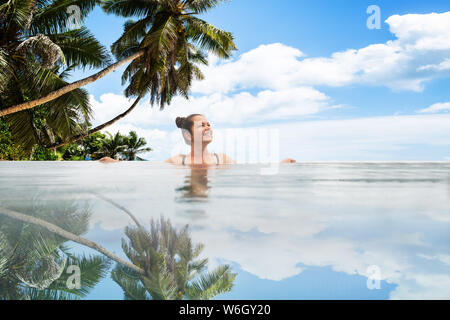 La photo d'une femme dans la piscine à débordement dans les montagnes Banque D'Images