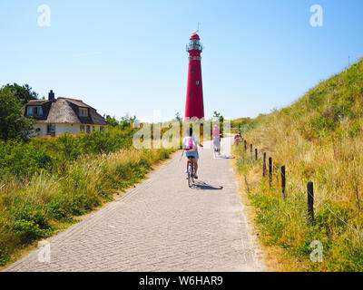 Retour Voir les cyclistes voyageant sur la route en direction de phare dans Schiermonnikoog, sur dune de sable sur fond de ciel bleu. La Hollande. Pays-bas Banque D'Images