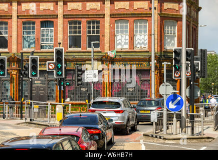 CARDIFF, WALES - Juillet 2019 : Voitures attente aux feux de circulation pour entrer dans les parkings dans le centre-ville de Cardiff. Dans l'arrière-plan est la croix d'or pub Banque D'Images