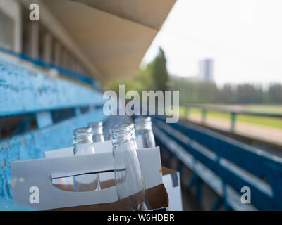 Close-up pack de bouteilles de bière vides laissés par des personnes sur stade vide après le sport match. selective focus avec arrière-plan flou . Banque D'Images