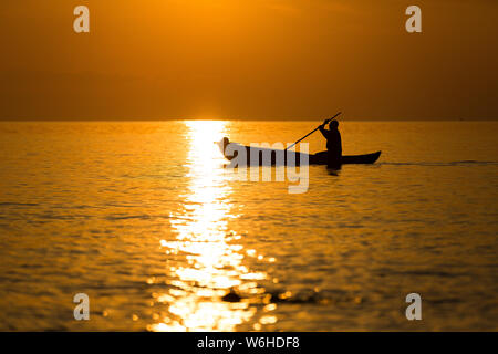 Les pêcheurs pirogue silhouette against orange lever du soleil sur le lac Malawi, le scintillement du soleil sur le lac, Sud-Est-Europe Banque D'Images