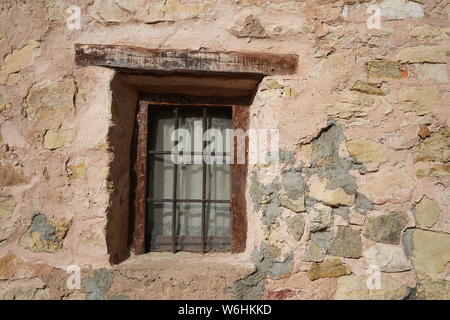 Petite fenêtre barrée avec un linteau en bois dans un mur en pierre brute et plâtre, Sigüenza, Espagne Banque D'Images