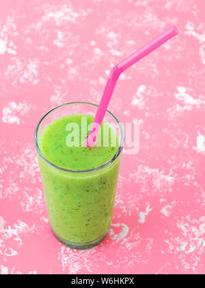 Concombre vert kiwi et banane smoothie santé dans un verre à cocktail rose tube sur un fond rose pastel. De savoureux plats végétariens frais boire. Vue d'en haut. Banque D'Images