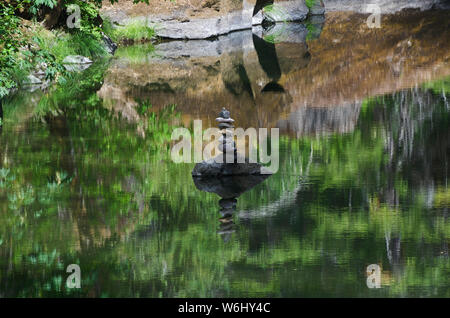 Ou : Douglas Co., Cascades. Réflexions de l'eau dans le sud de la rivière Umpqua, dans une section encore bordé de falaises, montrent une pile rock méditatif Banque D'Images