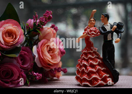 Close up de deux danseurs de flamenco, hommes et femmes. Univers miniatures ou souvenirs placé à côté d'un bouquet de roses roses. Banque D'Images