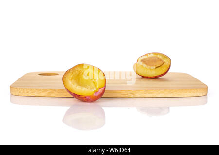 Groupe de deux moitiés de prune bleu frais avec une pierre sur une planche à découper en bambou isolé sur fond blanc Banque D'Images