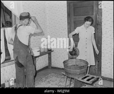 Mme Sergent Blaine se déverse l'eau du bain pour son mari ; cette société n'a pas de baignoire chambre ; il n'y a pas d'eau courante dans les maisons. P V & K Coal Company, trèfle, mine l'écart Lejunior, Harlan County, Kentucky. Banque D'Images