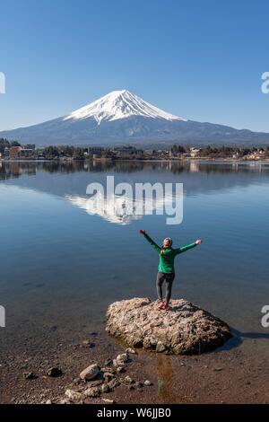 Jeune femme se dresse sur pierre dans l'eau et s'étire les bras en l'air, le lac Kawaguchi, volcan retour Mt. Fuji, préfecture de Yamanashi, Japon Banque D'Images