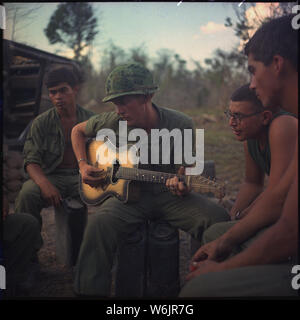 YELLOWSTONE OPÉRATION VIETNAM : Après une dure journée, quelques membres de la Compagnie A, 3e Bataillon, 22e Infanterie (mécanisé), 25e Division d'infanterie, se réunir autour d'un joueur de guitare et chanter quelques chansons. Banque D'Images