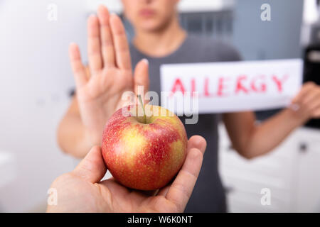 Woman Holding Apple refuse de carte d'Allergie offert par une personne à la maison Banque D'Images
