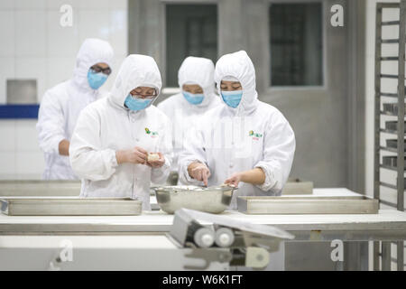 Les travailleurs chinois préparer des brioches à la vapeur sur la ligne de production à une usine de transformation des aliments de la Beijing Jingtie Service Co., Ltd. à Beijing, Chine, 7 Banque D'Images