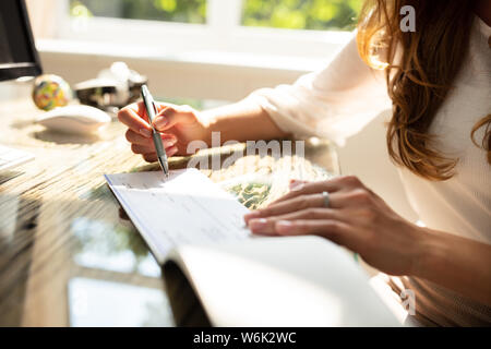 La main de femme Signature vérifier sur un bureau en bois Banque D'Images