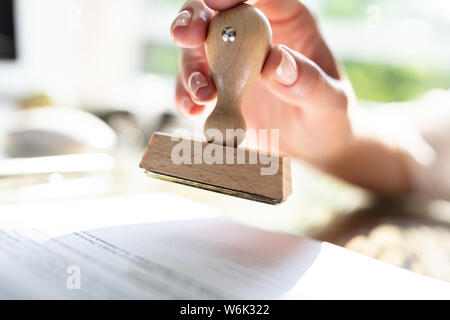 Close-up of Woman's Hand Stamping approuvée le papier du contrat avec Stamper Banque D'Images